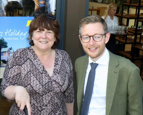 Louise Hillman manager of Keys Holiday Cottages cuts the 50th anniversary cake watched by Duncan Baker MP