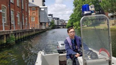 Brandon Thomas drives a Broads Auttority boat on the river in Norwich