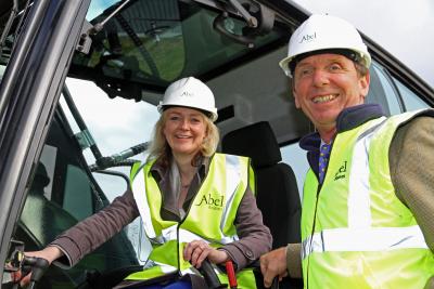 Elizabeth Truss at the controls of an excavator at the sod cutting ceremony at Swans Nest Swaffham aided by Tony Abel