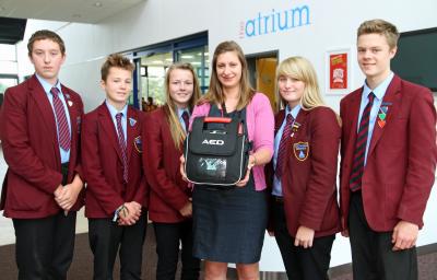 NWHS Communications and Events Manager Suzie Sharp holds the new defibrillator with students from each of the five Houses