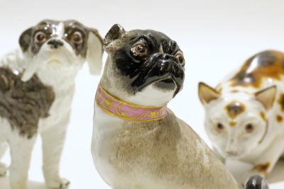 Three Meissen animal figures from left Bolognese terrier pug and crouching cat
